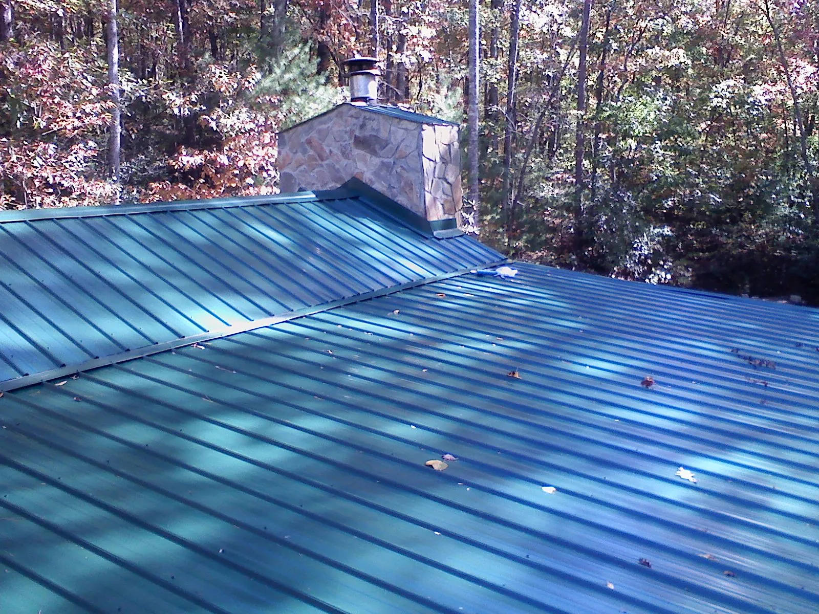 New green metal roof and stone chimney surrounded by autumn woods in Wharton