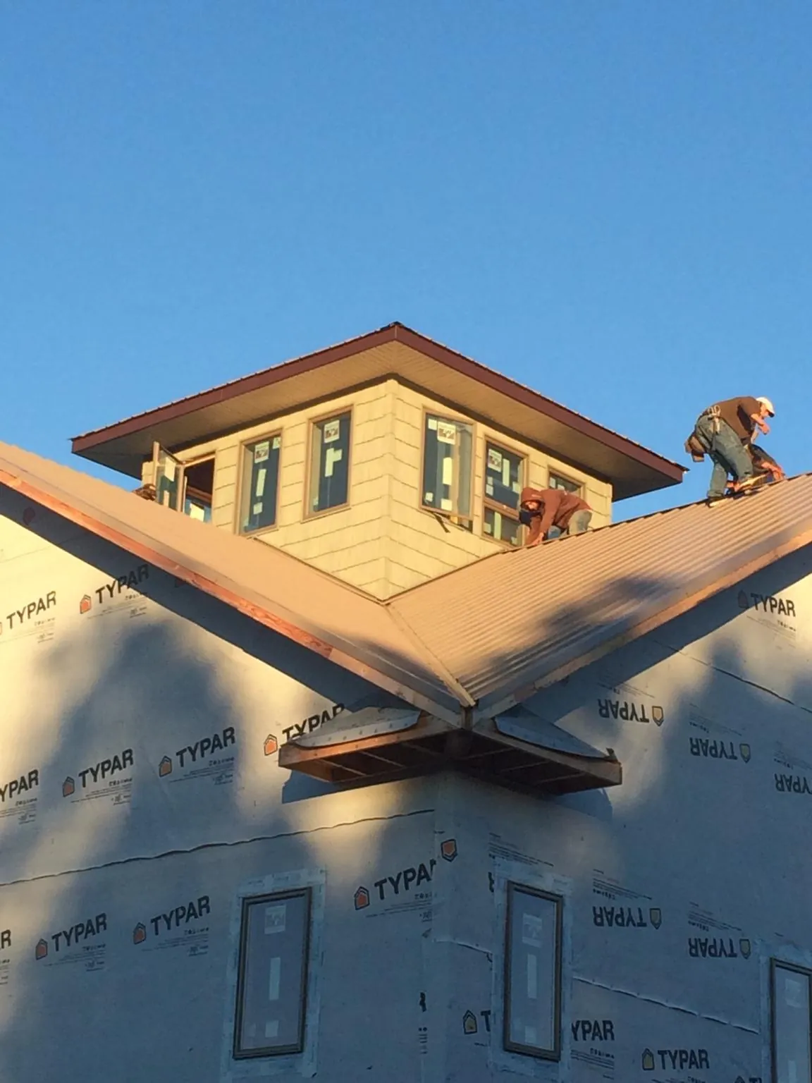 Roofers working around a rooftop cupola on a new metal roof at sunset — Roof Waterproofing in Wharton by Roofing Brothers